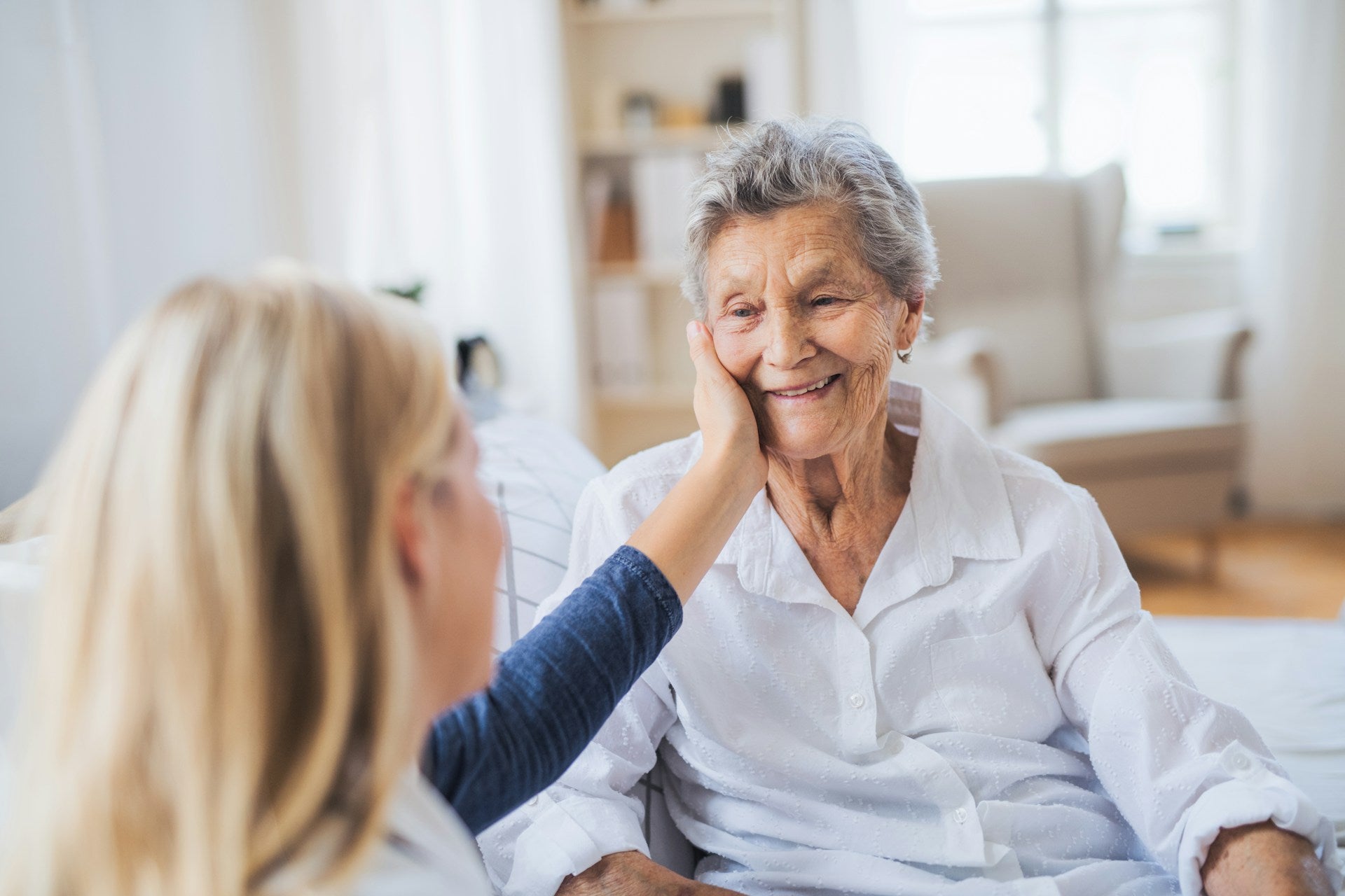 Older woman smiling as another woman gently touches her cheek