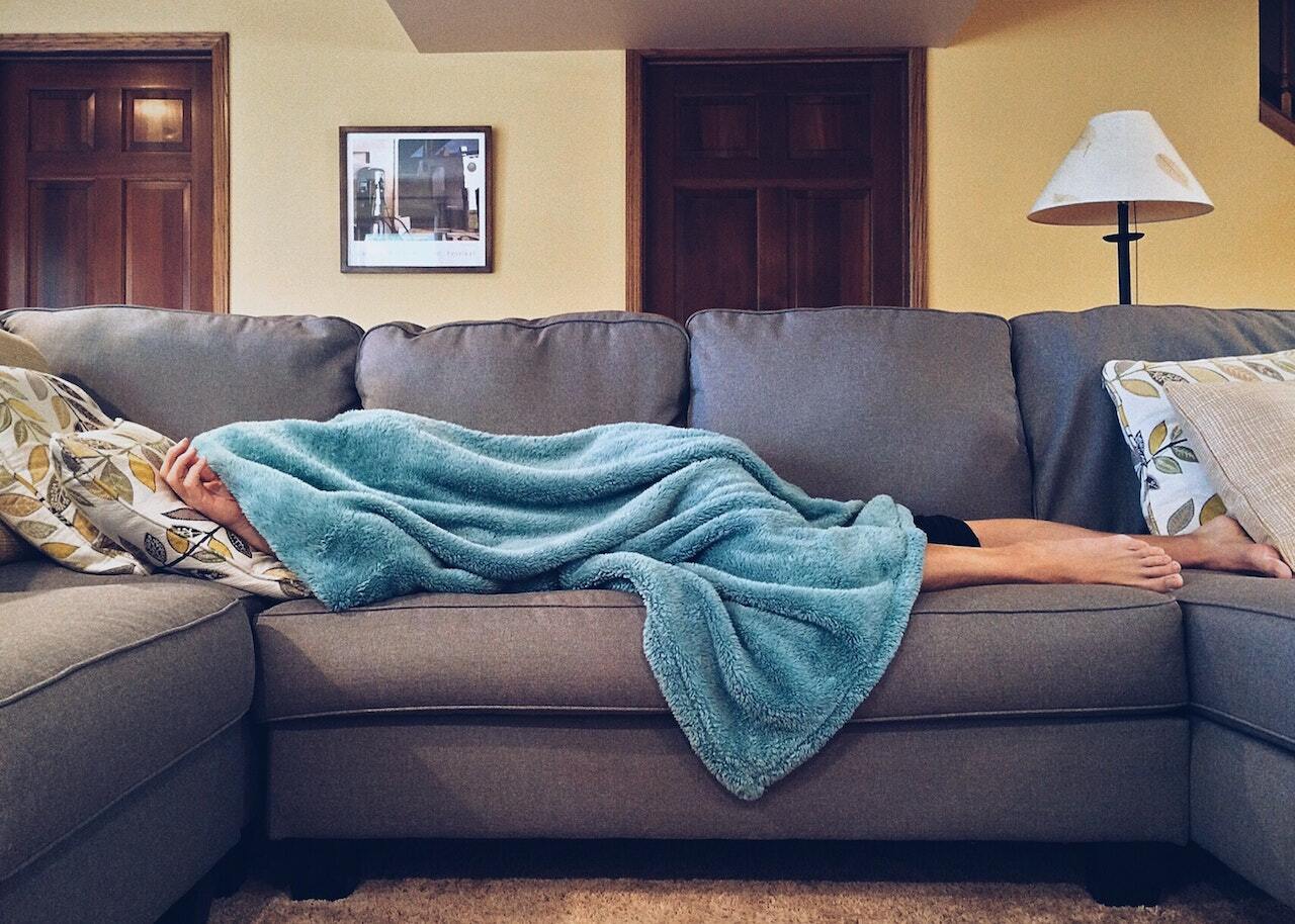 person lying on the couch under the blanket