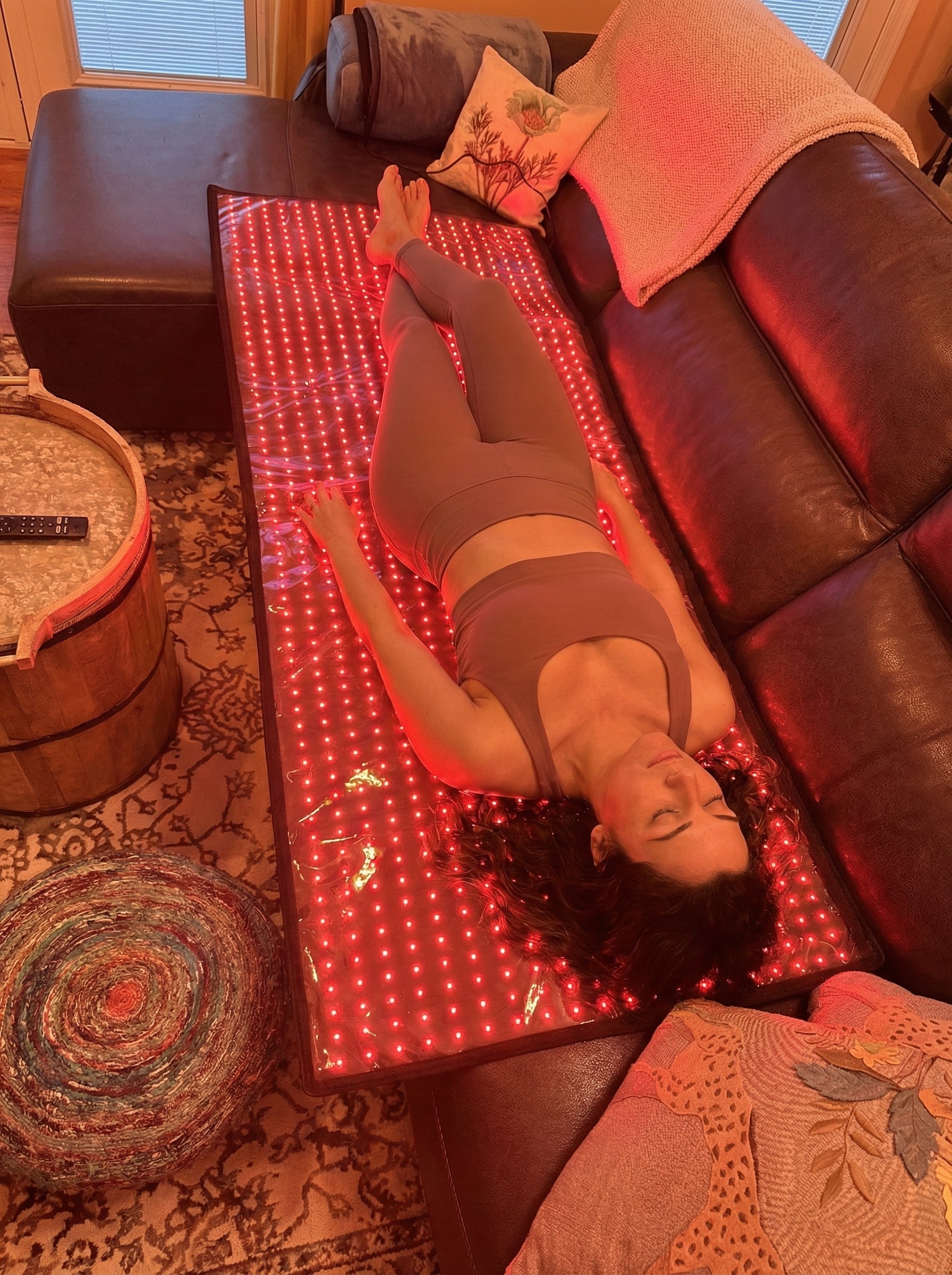 Woman resting on the red light mat at home